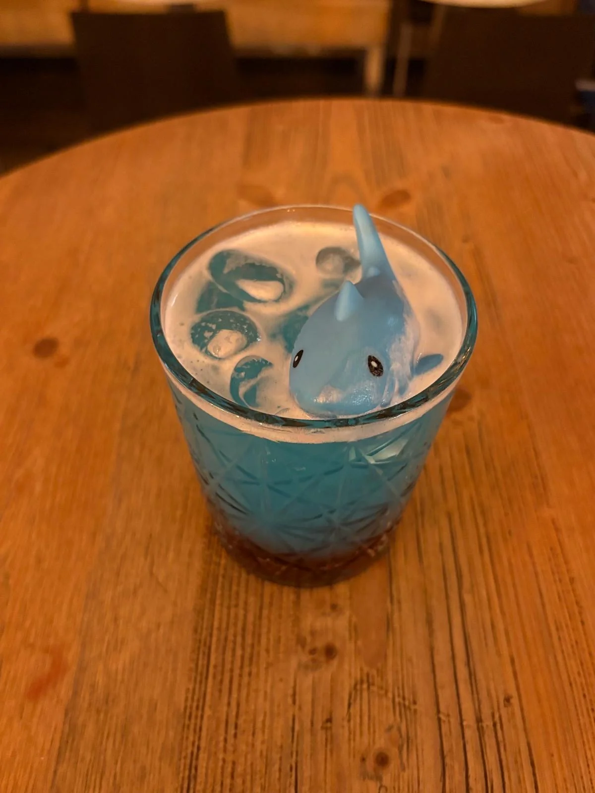 Cocktail blu con squalo decorativo sul tavolo in legno